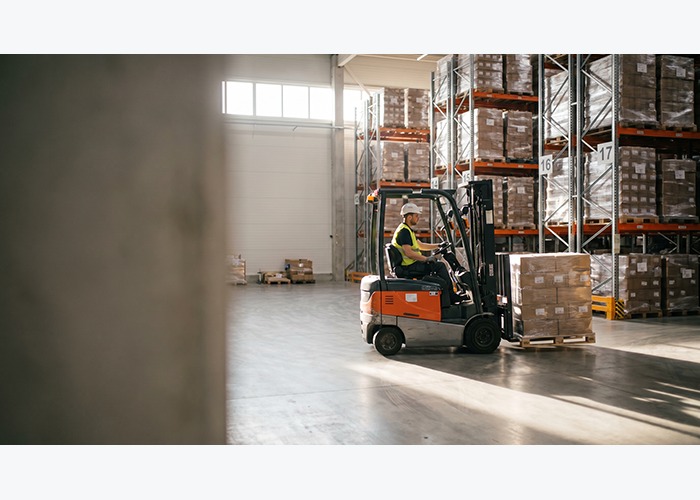 Electric forklift operating around pallet racks in an indoor facility