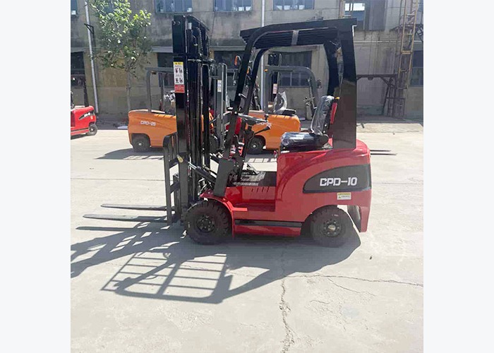 Compact electric forklift moving a pallet in an indoor warehouse lane